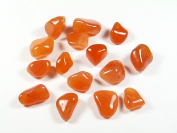 Kilka wypolerowanych kamieni karneolu leży na białym tle.