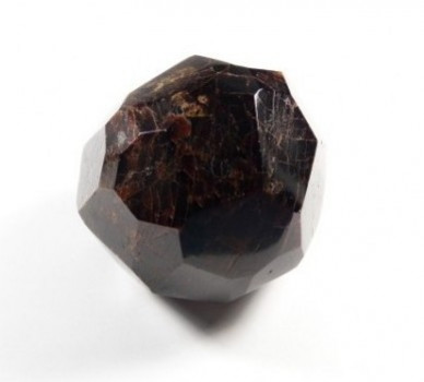 Granat almandyn okaz gładzony. Ciemny, oszlifowany kryształ granatu na białym tle.