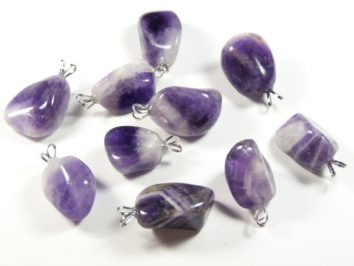 Dziewięć fioletowych kamieni ametystu z zawieszkami na białym tle.