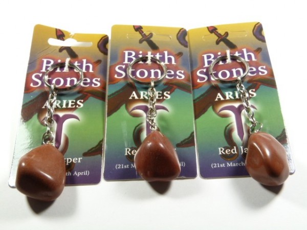 Trzy breloczki z czerwonym jaspisem na tle kart z napisem "Aries - Red Jasper".