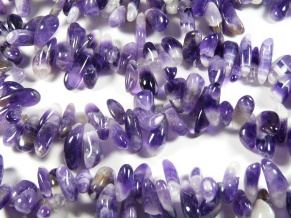 Naszyjnik z drobnych, polerowanych kamieni ametystu ułożonych na jasnym tle.