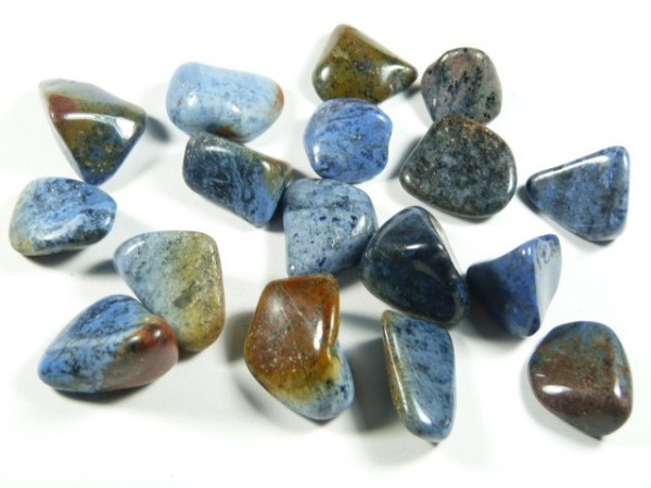 Wypolerowane niebiesko-brązowe kamienie szlachetne leżące na białym tle.
