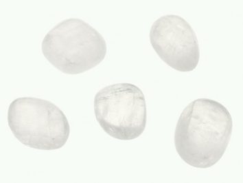Kalcyt biały - kamień gładzony, polerowany, szlifowany i bębnowany w formie otoczaka. Pięć gładkich, białych kamieni leży na jasnym tle.