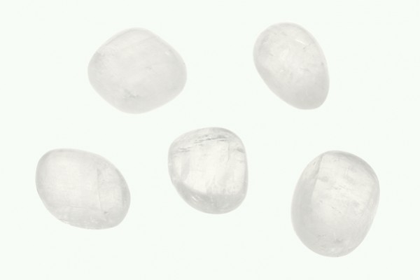 Kalcyt biały - kamień gładzony, polerowany, szlifowany i bębnowany w formie otoczaka. Pięć gładkich, białych kamieni leży na jasnym tle.
