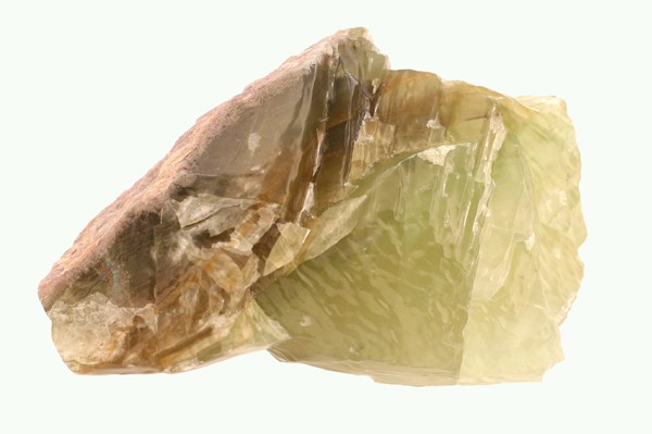 Zielonkawy kryształ selenitu na jasnym tle.