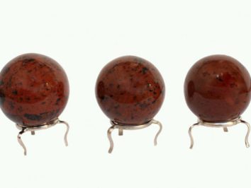 Trzy czerwono-brązowe kule z kamienia stojące na metalowych podstawkach.