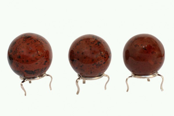 Trzy czerwono-brązowe kule z kamienia stojące na metalowych podstawkach.