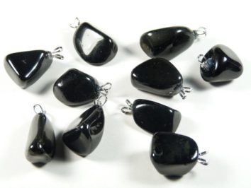 Dziewięć czarnych, błyszczących kamieni z zawieszkami do noszenia jako biżuteria, na białym tle.