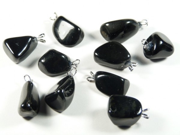 Dziewięć czarnych, błyszczących kamieni z zawieszkami do noszenia jako biżuteria, na białym tle.