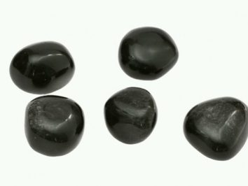 Pięć czarnych, wypolerowanych kamieni ułożonych na białym tle.