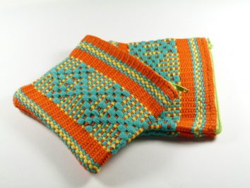 Dwie kolorowe, ręcznie robione saszetki z zamkiem błyskawicznym leżące na białym tle.