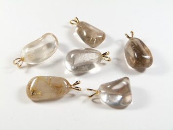 Sześć przezroczystych zawieszek z kryształu z metalowym uchwytem na białym tle.