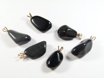 Sześć czarnych kamiennych zawieszek z metalowymi uchwytami leży na białym tle.