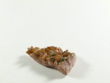 Dolomit - kamień naturalny, surowy, nieszlifowany. Kawałek minerału z brązowymi i zielonymi kryształami na białym tle.