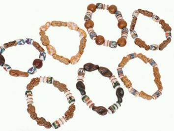 Siedem kolorowych bransoletek wykonanych z koralików ułożonych na białym tle.
