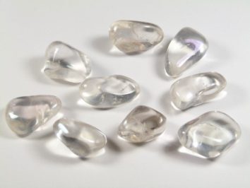 Dziewięć gładkich, przezroczystych kamieni leży na białym tle.