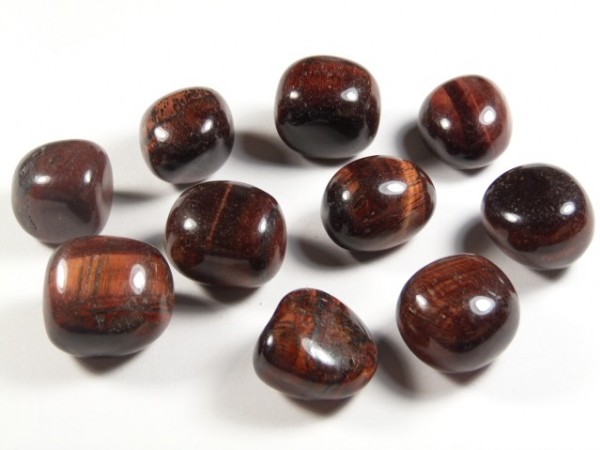Tygrysie oko czerwone/ bawole oko - kamień gładzony, polerowany, szlifowany i bębnowany w formie otoczaka. Dziesięć wypolerowanych kamieni tygrysiego oka leży na białym tle.
