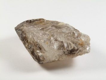 Przezroczysty, surowy kryształ minerału na białym tle.