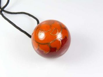 Wisior z okrągłym, pomarańczowo-czerwonym koralikiem na czarnym sznurku.