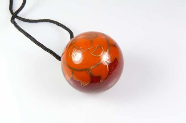 Wisior z okrągłym, pomarańczowo-czerwonym koralikiem na czarnym sznurku.