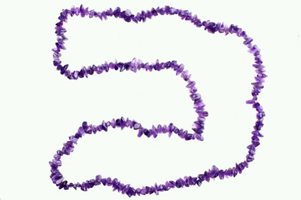 Naszyjnik z fioletowych kamieni ułożony na białym tle.