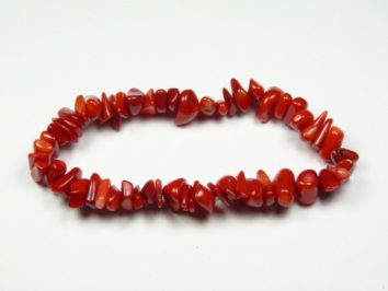 Czerwona bransoletka z nieregularnych koralików z kamieni na białym tle.