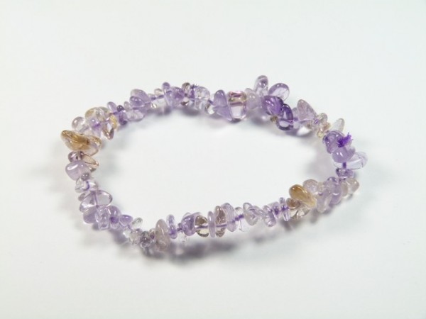 Bransoletka z fioletowych i przezroczystych kamieni na białym tle.