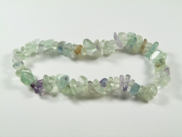 Bransoletka z drobnych, kolorowych kamieni na elastycznej żyłce, leży na białym tle.