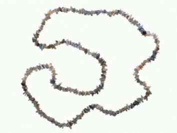 Naszyjnik z drobnych, nieregularnych kamieni na jasnym tle.