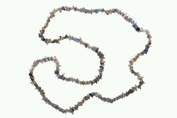 Naszyjnik z drobnych, nieregularnych kamieni na jasnym tle.