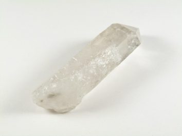 Przezroczysty kryształ kwarcu leżący na białym tle.