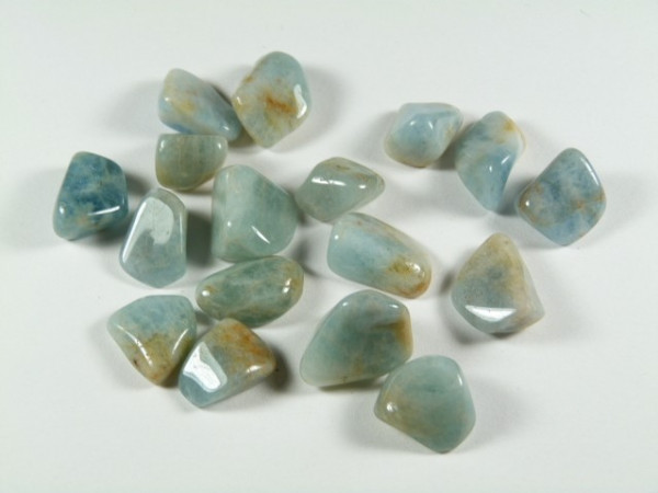 Kilka niebieskozielonych, wypolerowanych kamieni leży na białym tle.