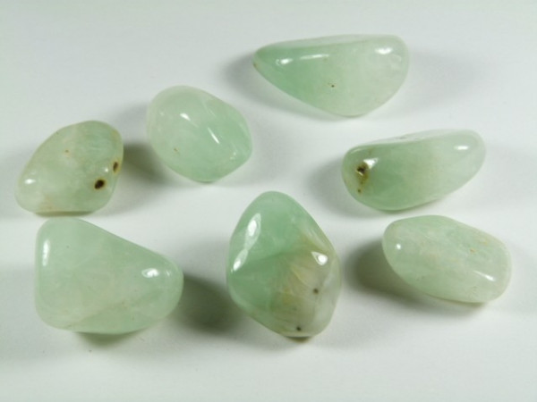 Sześć zielonych, oszlifowanych kamieni leży na białym tle.