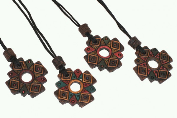 Cztery kolorowe, ozdobne wisiorki na czarnych sznurkach ułożone obok siebie.