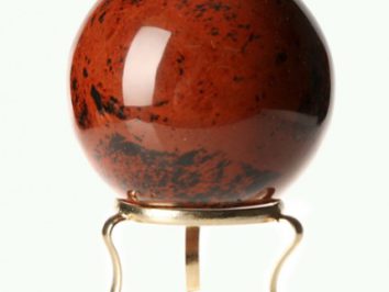 Czerwona kula z czarnego jaspisu na metalowym stojaku na białym tle.