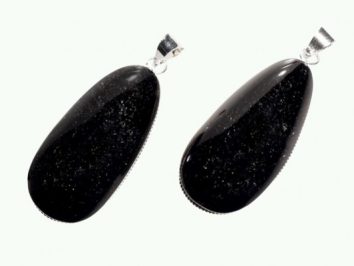 Dwa czarne, błyszczące wisiorki z kamienia z metalowym uchwytem na jasnym tle.