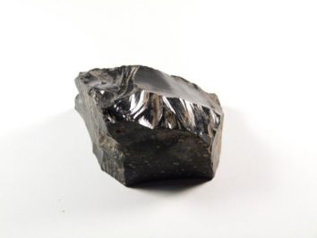 Czarny kawałek obsydianu na białym tle.