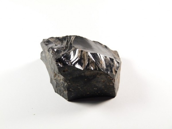 Czarny kawałek obsydianu na białym tle.