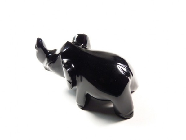 Czarna, połyskująca figurka nosorożca na białym tle.