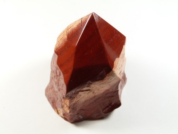 Czerwony, oszlifowany kamień jaspisu na białym tle.