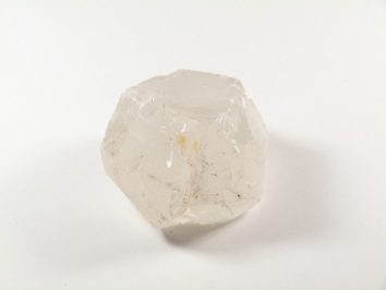 Przezroczysty kryształ kwarcu leży na białym tle.