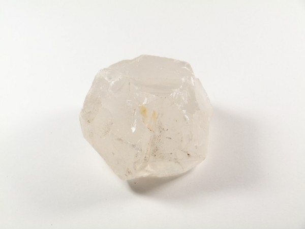 Przezroczysty kryształ kwarcu leży na białym tle.