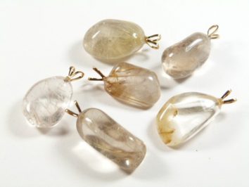 Sześć przezroczystych kamieni wisiorków z metalowymi uchwytami na białym tle.