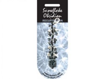 Wisiorek z obsydianu śnieżnego na zawieszce, na tle jasnych wzorów.