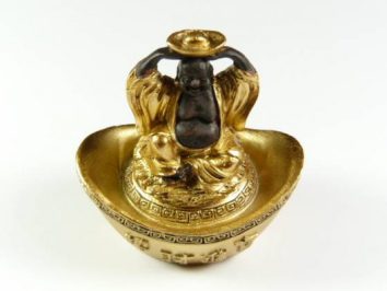 Budda miniaturowy figurka. Złota figurka Buddy siedzącego, trzymającego monetę nad głową.