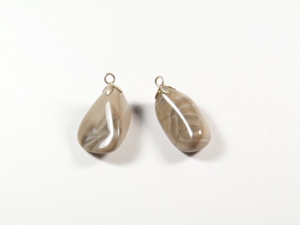 Dwa jasnobrązowe wisiorki z kamieni naturalnych na białym tle.