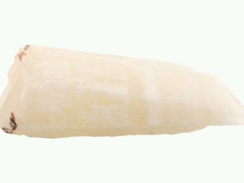 Biały kryształowy kamień, leży na jasnym tle.