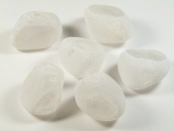 Sześć białych, matowych kamyków leży na białym tle.