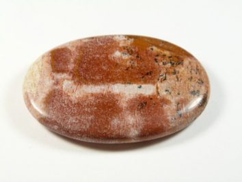 Jaspis obrazkowy - kamień gładzony, polerowany, szlifowany. Gładki, owalny kamień jaspisu o czerwonobrązowym i kremowym zabarwieniu na białym tle.