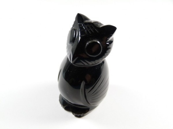 Czarna figurka sowy wykonana z połyskującego kamienia na białym tle.